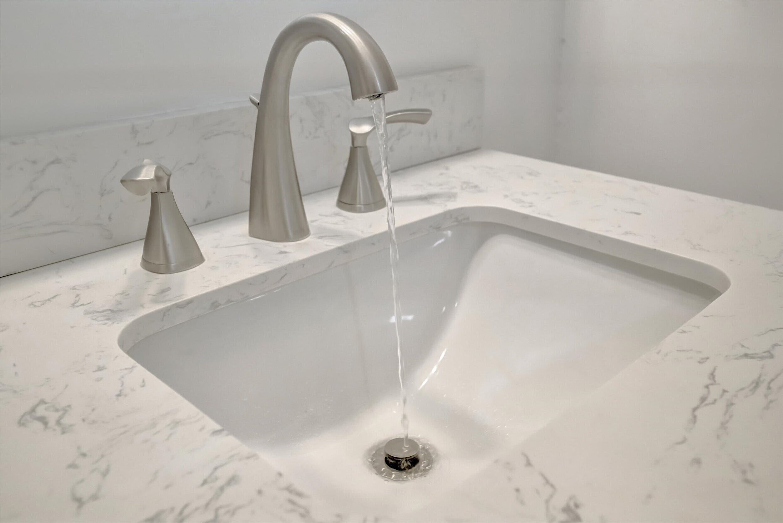 A modern bathroom sink with a single faucet and a drain.
