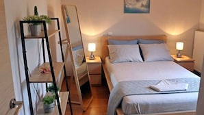 A neatly arranged bedroom with a bed, bedside tables, a mirror, and a wall-mounted painting. - Villa Amorata - Schinias Private Garden Retreat (Marathon)