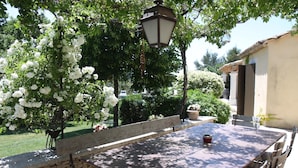 Un patio al aire libre con un muro de piedra, un banco de madera y una mesa con sillas.