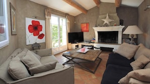 Una sala de estar con chimenea, televisor y una mesa de centro.
