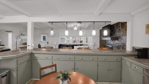 A kitchen with a central island, pendant lights, and a stone backsplash. - Lakefront Cabin With Private Dock (Eclectic)
