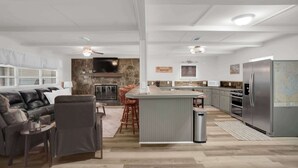 A modern kitchen with a central island, a dining area with a stone wall, and a living room with a leather sofa. - Lakefront Cabin With Private Dock (Eclectic)