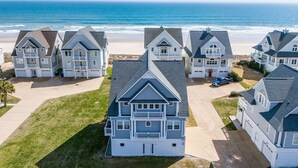 Uma área residencial costeira com várias casas, uma praia e uma vista clara do oceano.