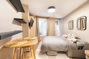 Un dormitorio con cama, escritorio, silla y ventana.