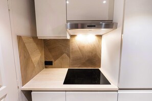 Una cocina con estufa integrada, campana extractora de acero inoxidable y paneles de madera en las paredes.