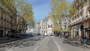 A cobblestone street lined with historic buildings, a tram, and bicycles. - Appartement 2BR lumineux et raffiné - Opéra (Paris)
