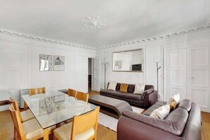 Ein modernes Wohnzimmer mit einem Glastisch, Ledersofas und einem großen Spiegel.