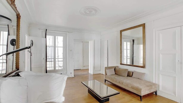 A spacious living room with a large mirror, a sofa, and a coffee table. - Appartement 2BR lumineux et raffiné - Opéra (Paris)