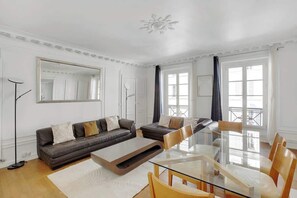 Ein modernes Wohnzimmer mit einem Glastisch, zwei Sofas und einem großen Spiegel.