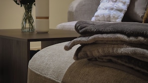A room with a sofa, a vase with flowers, and a stack of towels on a table. - Prestige Apartment Centre Agdal Rabat (Rabat)