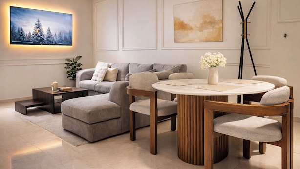 A modern living room with a sectional sofa, a round wooden table with chairs, a TV mounted on the wall, and artwork above the sofa. - Prestige Apartment Centre Agdal Rabat (Rabat)