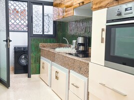 Una cocina con lavadora, cafetera y microondas.
