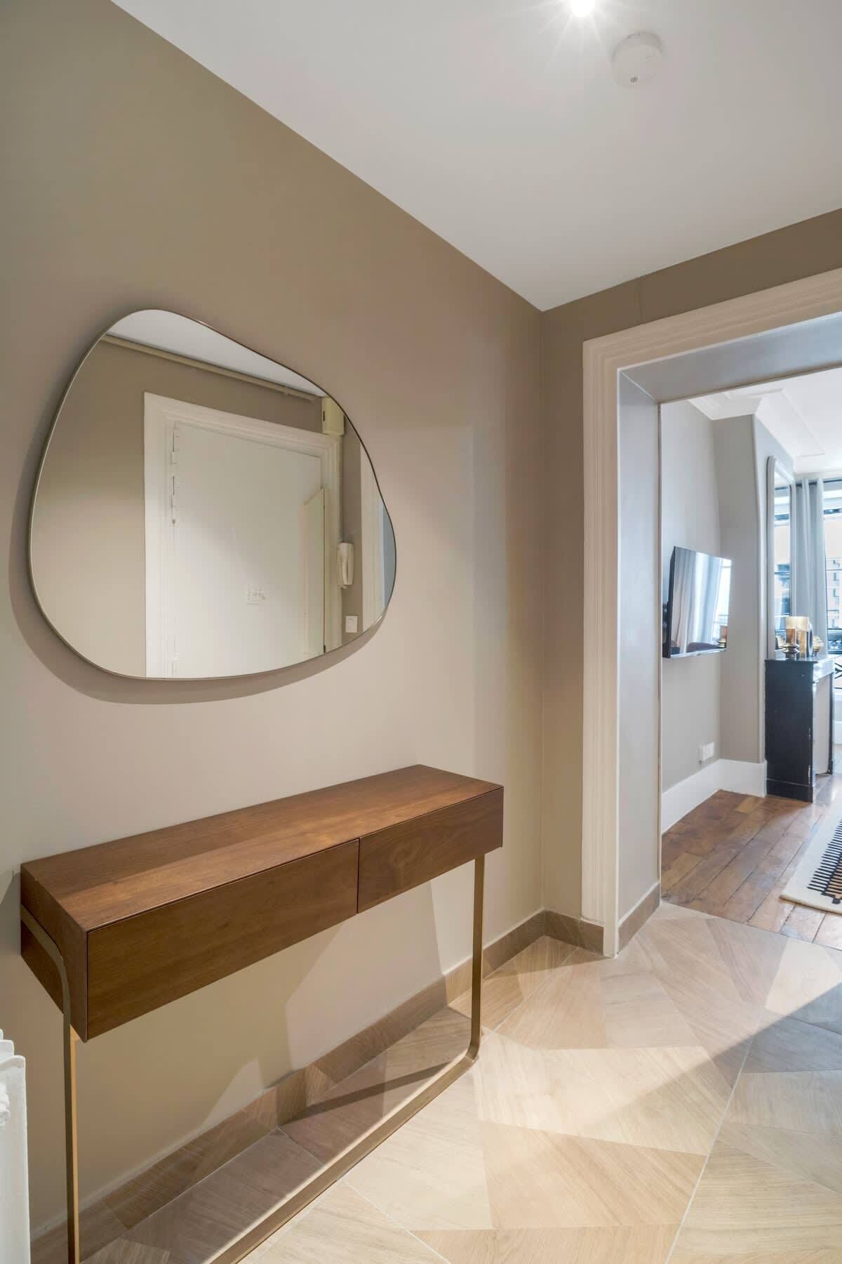 Un couloir moderne avec une console en bois et un grand miroir.