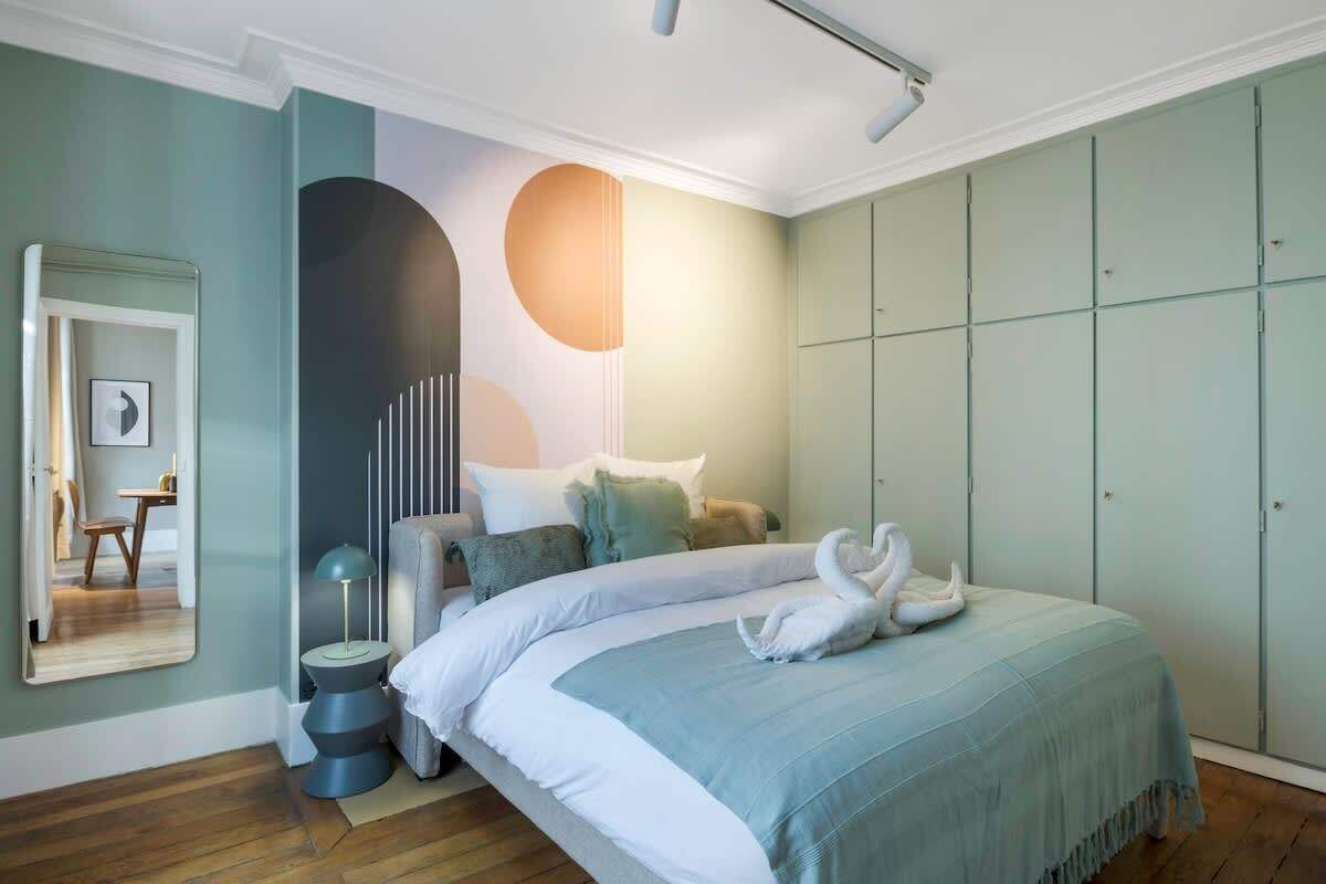 Ein Schlafzimmer mit einem Bett, einem Nachttisch, einer Lampe, einem Spiegel und einem Kleiderschrank.