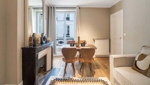 A modern living room with a fireplace, a dining area with chairs, and a view of the city through large windows. - Modern apartment with AC in the heart of the 7th arrondissement (Paris)