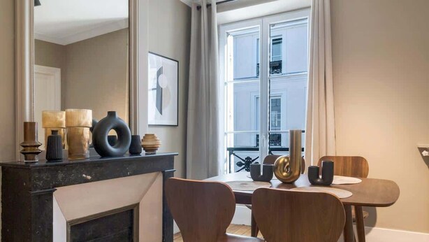 A modern dining area with a fireplace, wooden chairs, and a large mirror. - Modern apartment with AC in the heart of the 7th arrondissement (Paris)
