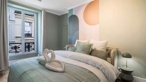 A bedroom with a bed, a nightstand, a lamp, and a window with curtains. - Modern apartment with AC in the heart of the 7th arrondissement (Paris)
