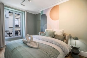 A bedroom with a bed, a nightstand, a lamp, and a window with curtains. - Modern apartment in the heart of the 7th arrondissement (Paris)