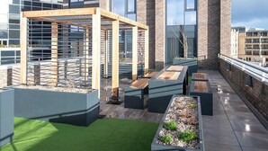 A rooftop terrace with a wooden pergola, seating areas, and planters. - Student Only Haymarket Yard (Edinburgh)