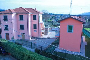 Un bâtiment rose avec un toit rouge, un escalier et une petite structure adjacente.