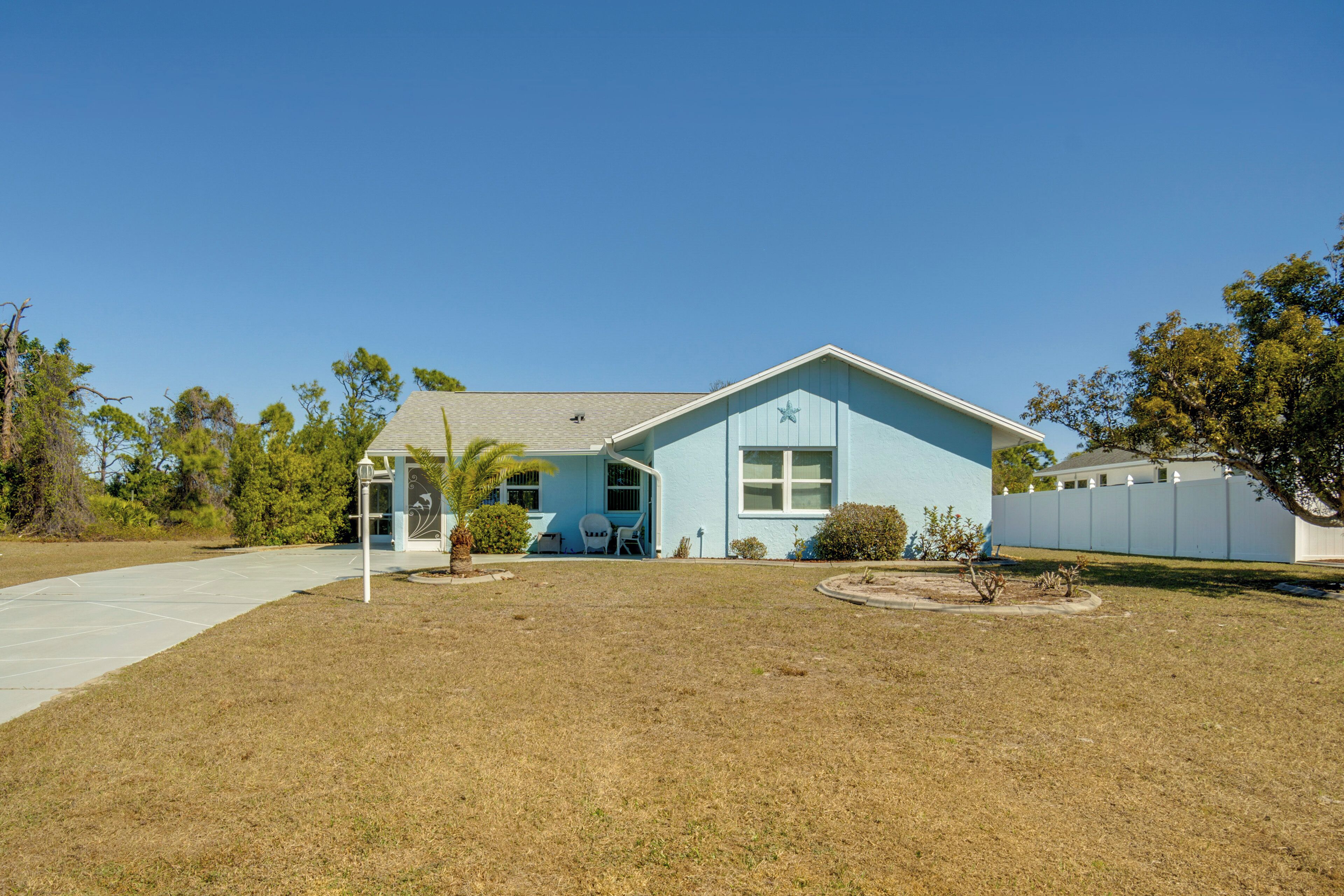 A light blue house with a star on the front, a small patio, and a clear blue sky.