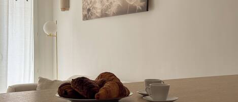 Una mesa de comedor con un plato de croissants y una taza y platillo.
