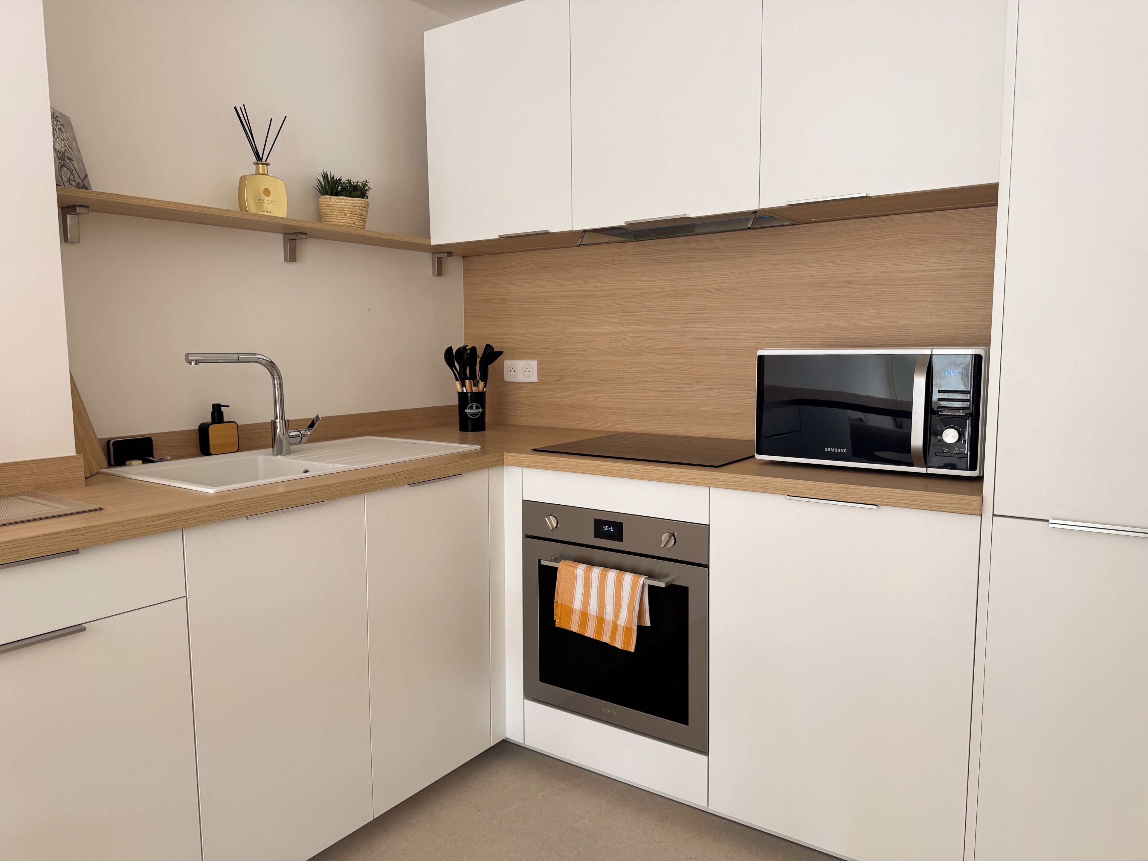 Una cocina moderna con fregadero, microondas, horno y encimera de madera.
