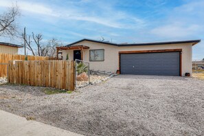 A single-story house with a garage, a wooden fence, and a gravel driveway. - Fully Renovated, Near Nmsu! Convenient Family Home (Las Cruces)