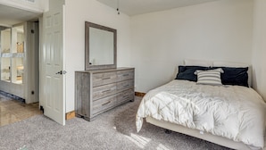 A bedroom with a bed, a dresser, a mirror, and a ceiling fan.