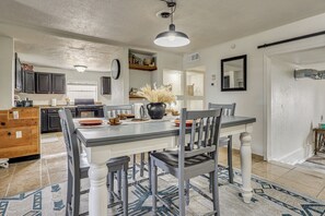 A modern kitchen with dark cabinets, a central island, and a dining area with a table and chairs. - Fully Renovated, Near Nmsu! Convenient Family Home (Las Cruces)