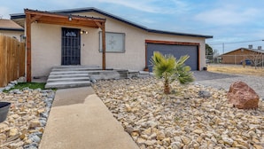 A single-story house with a garage, a covered entryway, and a small palm tree in the front yard.