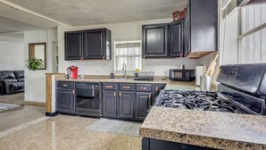 A modern kitchen with dark cabinetry, a granite countertop, and a gas stove.