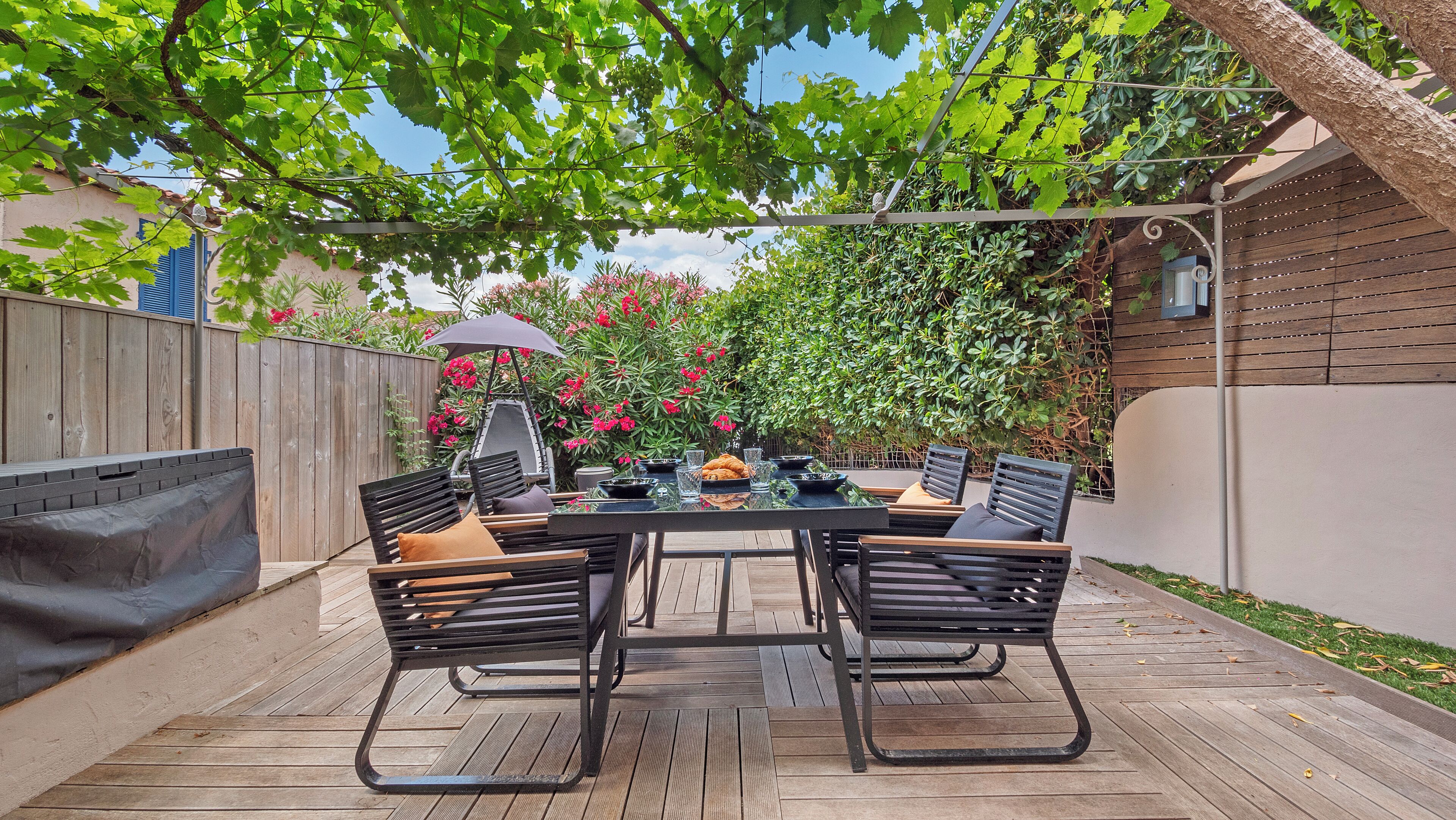 A patio with a table and chairs, surrounded by a wooden deck and a wooden fence.