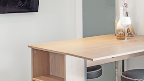 A modern room with a wooden table, two shelves with wine glasses, a black chair, and a wall-mounted picture. - Happy Tropez: Authentic village house with terrace, in the heart of Gassin. (Gassin)
