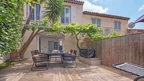 A patio with a table and chairs, a covered grill, and a wooden fence. - Happy Tropez: Authentic village house with terrace, in the heart of Gassin. (Gassin)