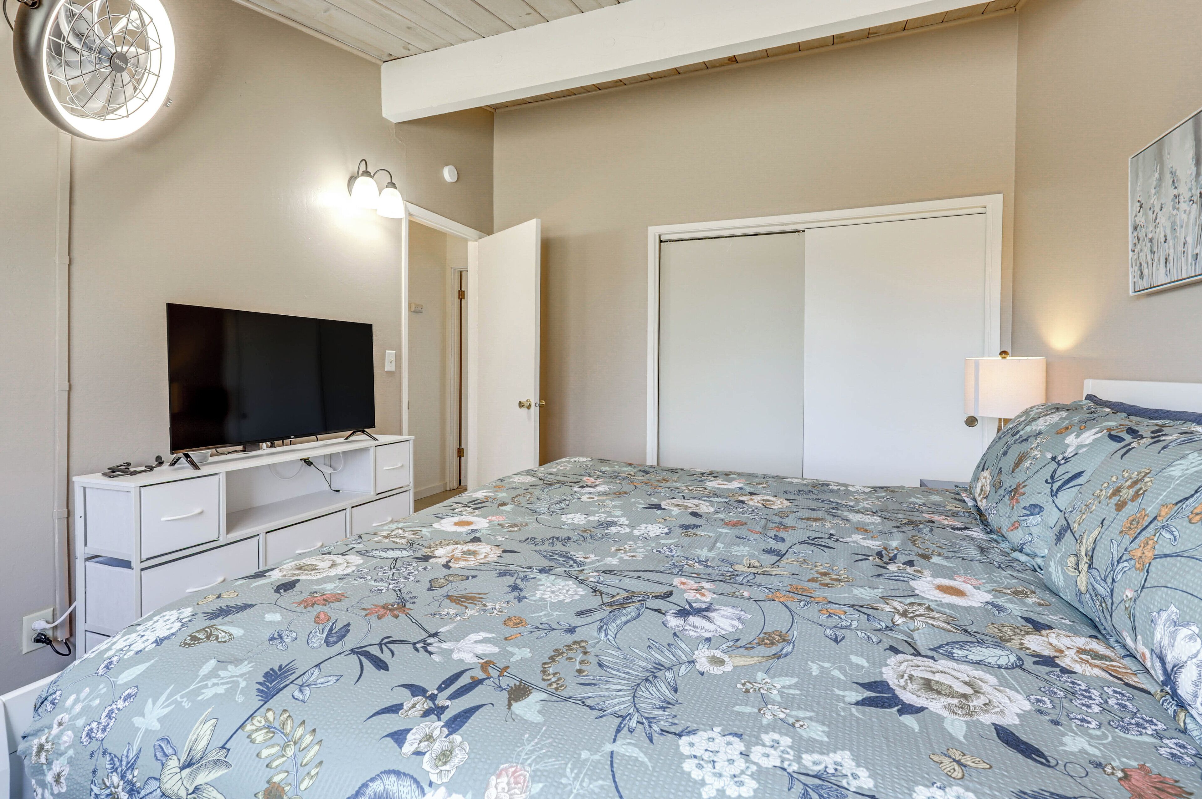 Een slaapkamer met een bed, een televisie, een kaptafel en een kledingkast.