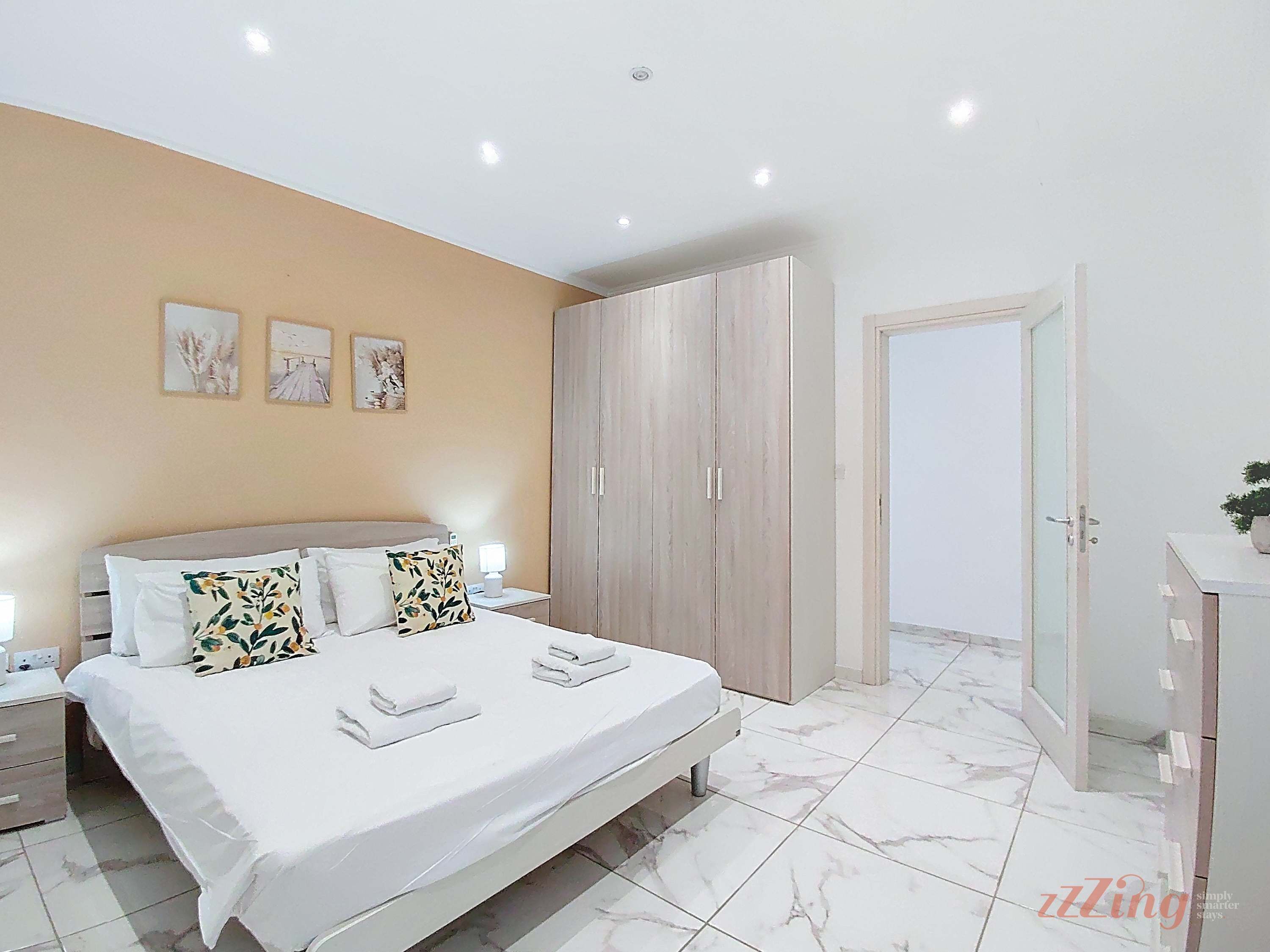 Une chambre à coucher avec un lit, des tables de chevet, une armoire et une porte.