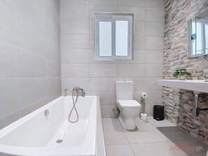 A modern bathroom with a bathtub, toilet, and sink. - Premium Seafront Apartment with Panoramic Bay Views (Il-Mellieħa)