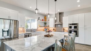 A modern kitchen with white cabinets, stainless steel appliances, and a marble island. - Poolside Paradise & Boat Dock! Haven on Lake Clay (Lake Placid)