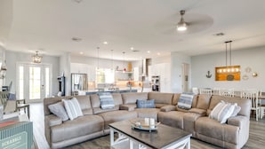 A spacious living room with a sectional sofa, a coffee table, and a kitchen in the background. - Poolside Paradise & Boat Dock! Haven on Lake Clay (Lake Placid)