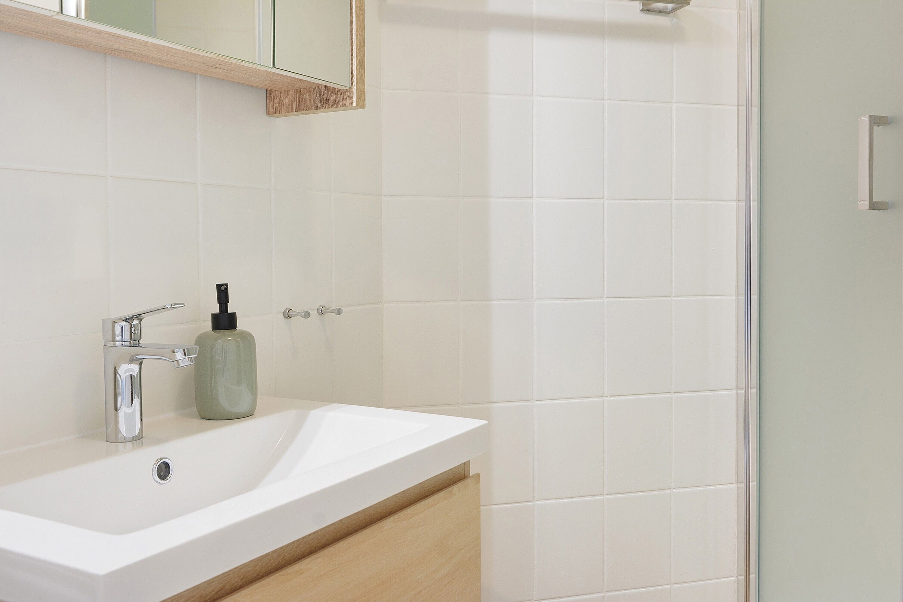 A bathroom with a white sink, chrome faucet, and a mirror above it.