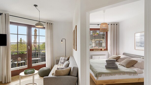 Un dormitorio moderno con cama, sofá y vistas al exterior.