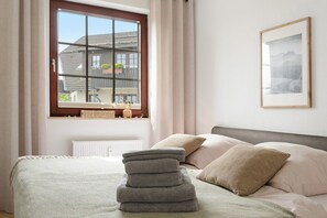 Una camera da letto con un letto, cuscini, una finestra e un quadro appeso al muro.