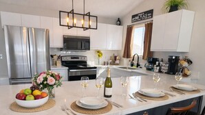 A modern kitchen with a central island, stainless steel appliances, and a welcoming sign. - Stillwater Shores Lakefront 2bd/2BA Pool, Hot Tub 6PP (Village of Four Seasons)
