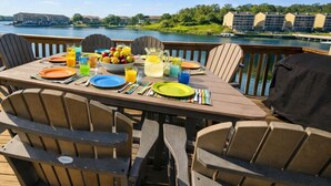 A wooden deck with a table set for breakfast, overlooking a lake with buildings in the background. - Stillwater Shores Lakefront 2bd/2BA Pool, Hot Tub 6PP (Village of Four Seasons)