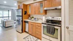 A modern kitchen with wooden cabinets, stainless steel appliances, and a built-in oven. - Golf, Swim & Dine! Condo w/ Lake Conroe Access (Montgomery)