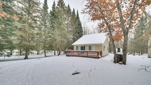 A cabin with a snow-covered deck and a wooden fence, surrounded by trees and a snowy landscape. - Family Nature Escape! South Branch Haven w/ Deck (South Branch)