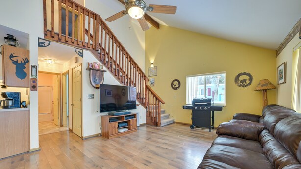 A spacious living room with a wooden staircase, a brown leather sofa, and a television on a wooden stand. - Family Nature Escape! South Branch Haven w/ Deck (South Branch)