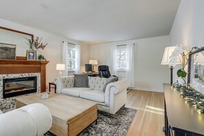 A living room with a fireplace, a sofa, a coffee table, and a lamp. - Spacious Home Near Lake Bemidji With Game Room! (Bemidji)