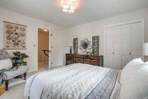 A bedroom with a large bed, a dresser, a chair, and a door leading to another room. - Spacious Home Near Lake Bemidji With Game Room! (Bemidji)